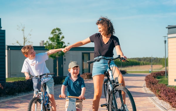 A woman and two kids enjoying a bike ride on a charming brick path.