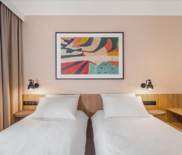 A hotel room featuring two comfortable beds, arranged for a relaxing stay, with warm colors enhancing the ambiance.