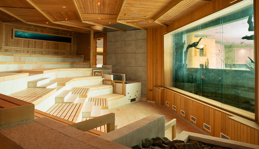 A cozy sauna room with wooden walls, featuring a large aquarium, adding a serene touch to the space.