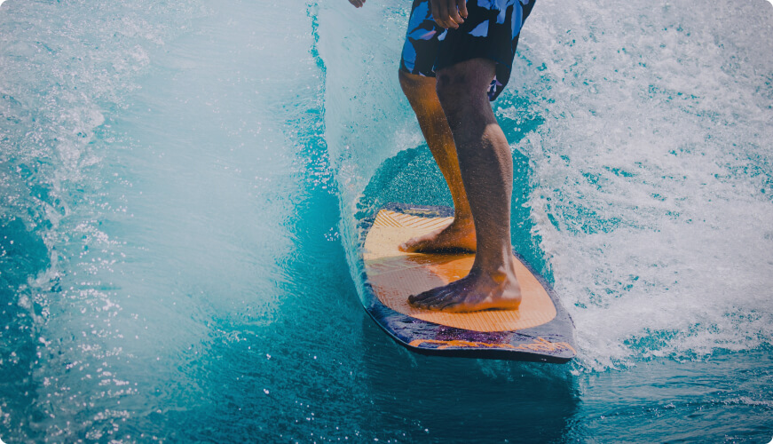 A surfer balances on a surfboard, gliding over a wave.
